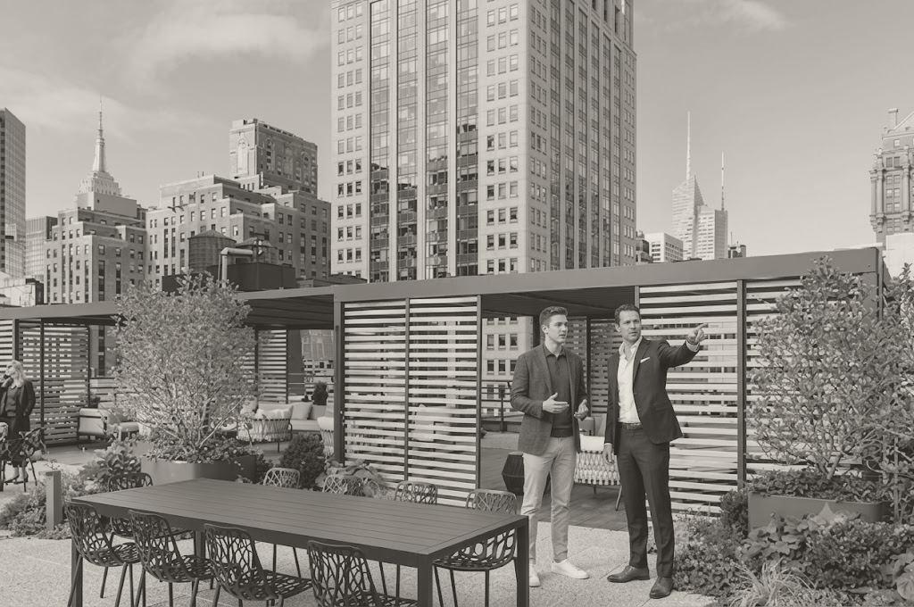 Two men talking on a Midtown roof terrace with planting, slatted timber screens and skyscrapers behind